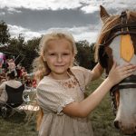 Girl standing next to a horse